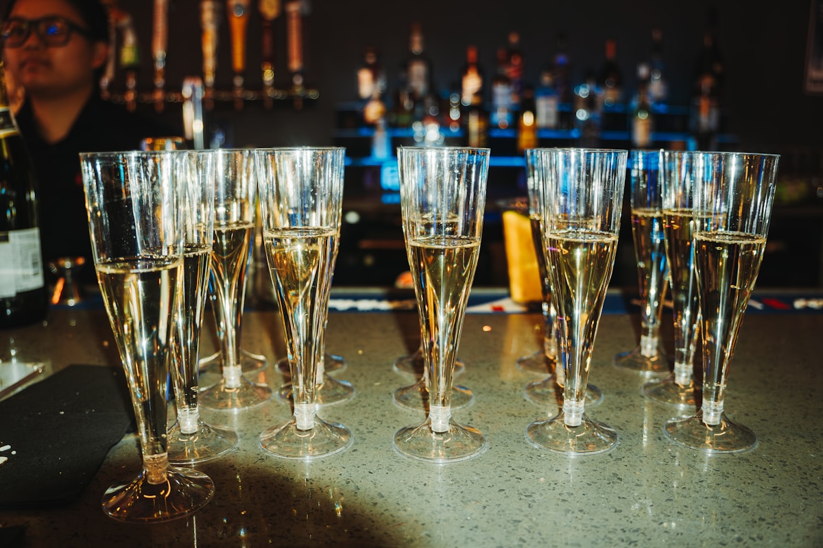 Flûtes de champagne sur un comptoir de bar sombre.