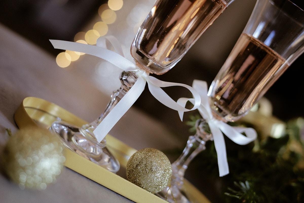 Verres de champagne avec rubans blancs et boules dorées scintillantes.