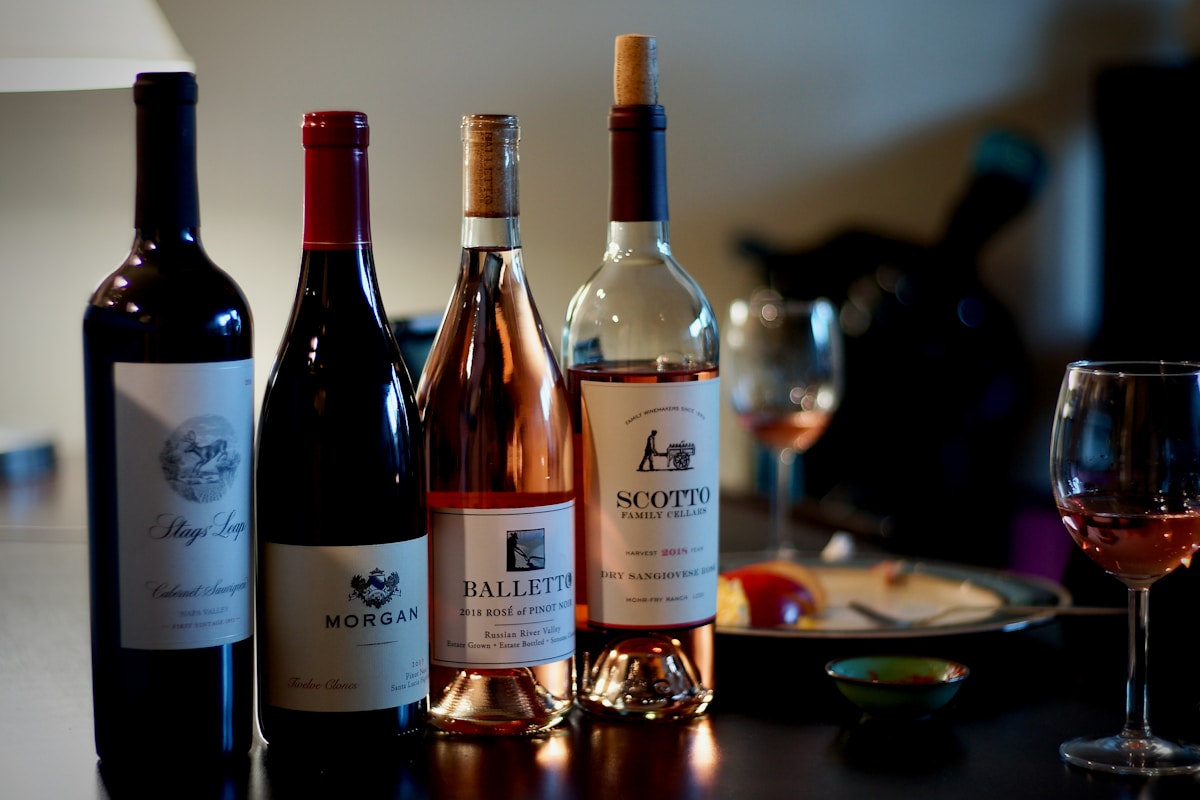 Bouteilles de vin de différents cépages et millésimes, verres à vin, ambiance feutrée.