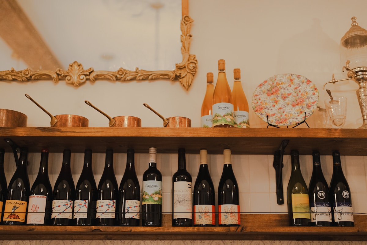 Étagère en bois avec bouteilles de vin et ustensiles de cuisine.