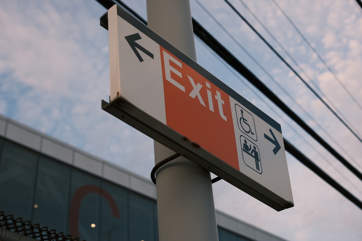 Panneau de signalisation indiquant la sortie, avec des symboles d'accessibilité.