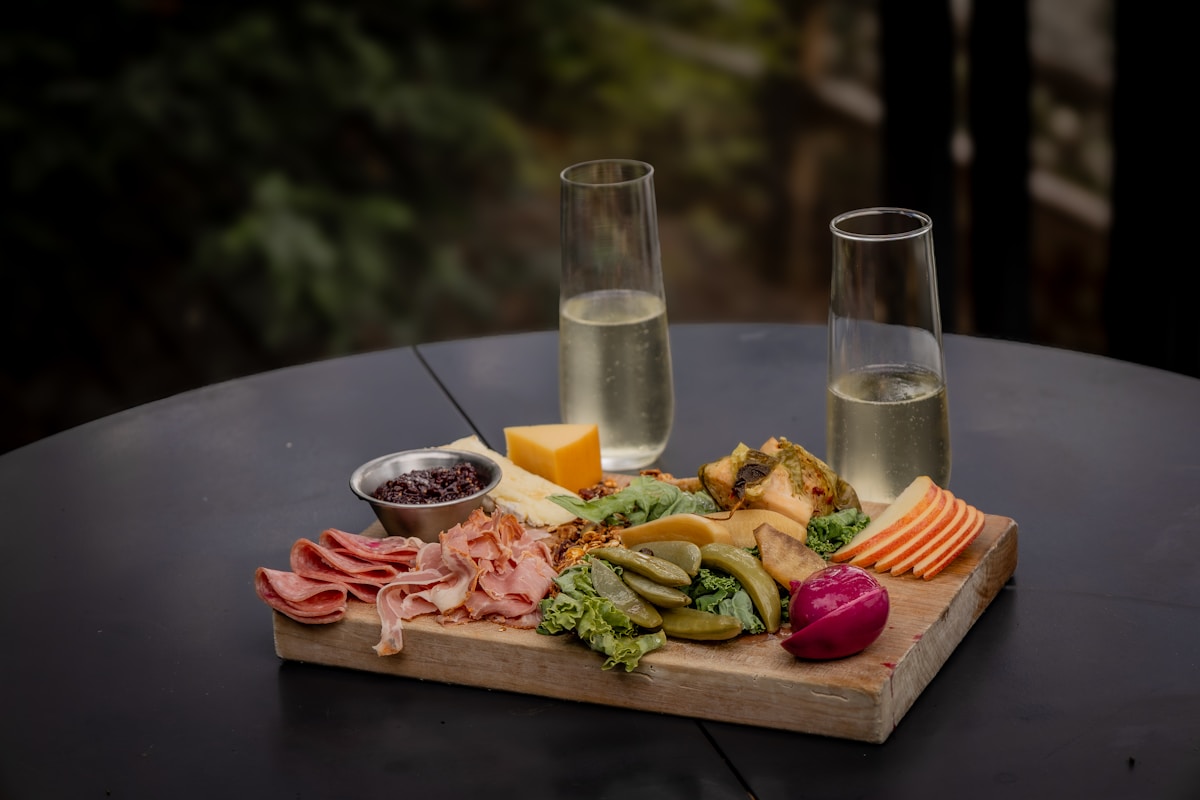 Plateau de charcuterie et de légumes avec deux verres de champagne.