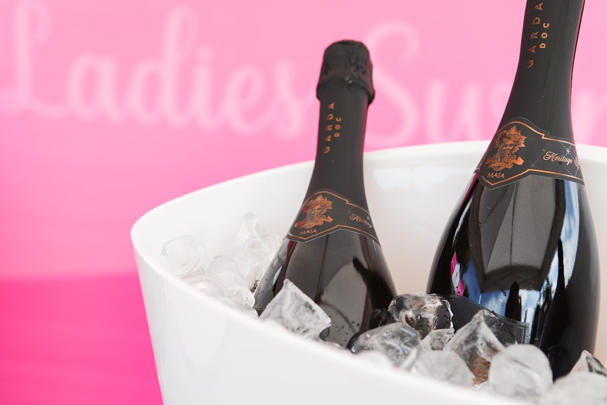 Bouteilles de champagne dans un seau de glace sur fond rose.