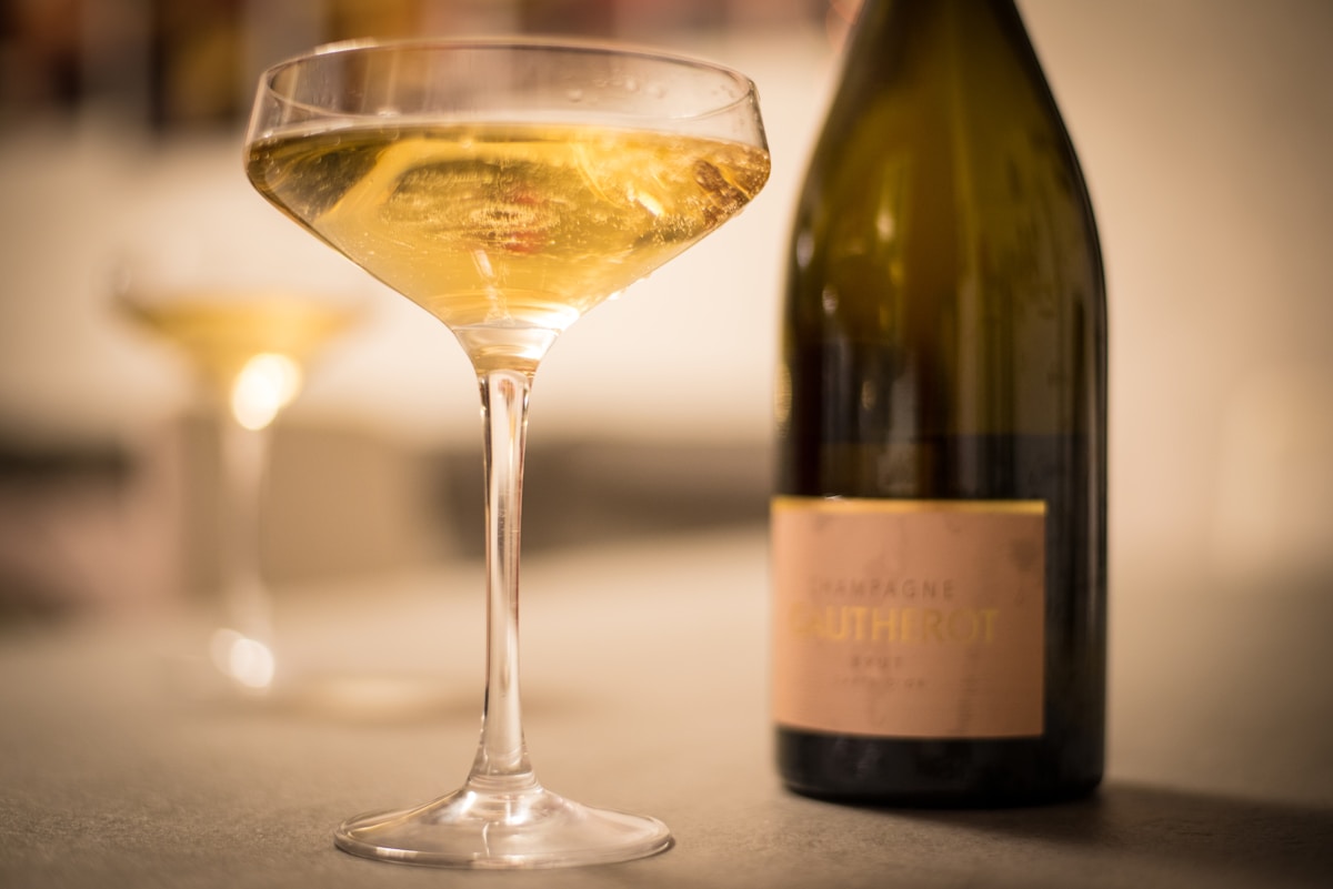 Verre de vin blanc élégant avec bouteille de vin en arrière-plan.
