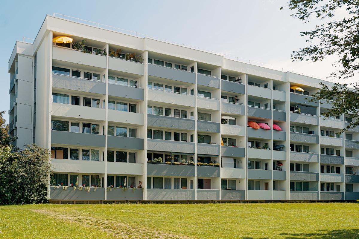 Mehrstöckiges Wohngebäude mit Balkonen und Grünfläche davor.