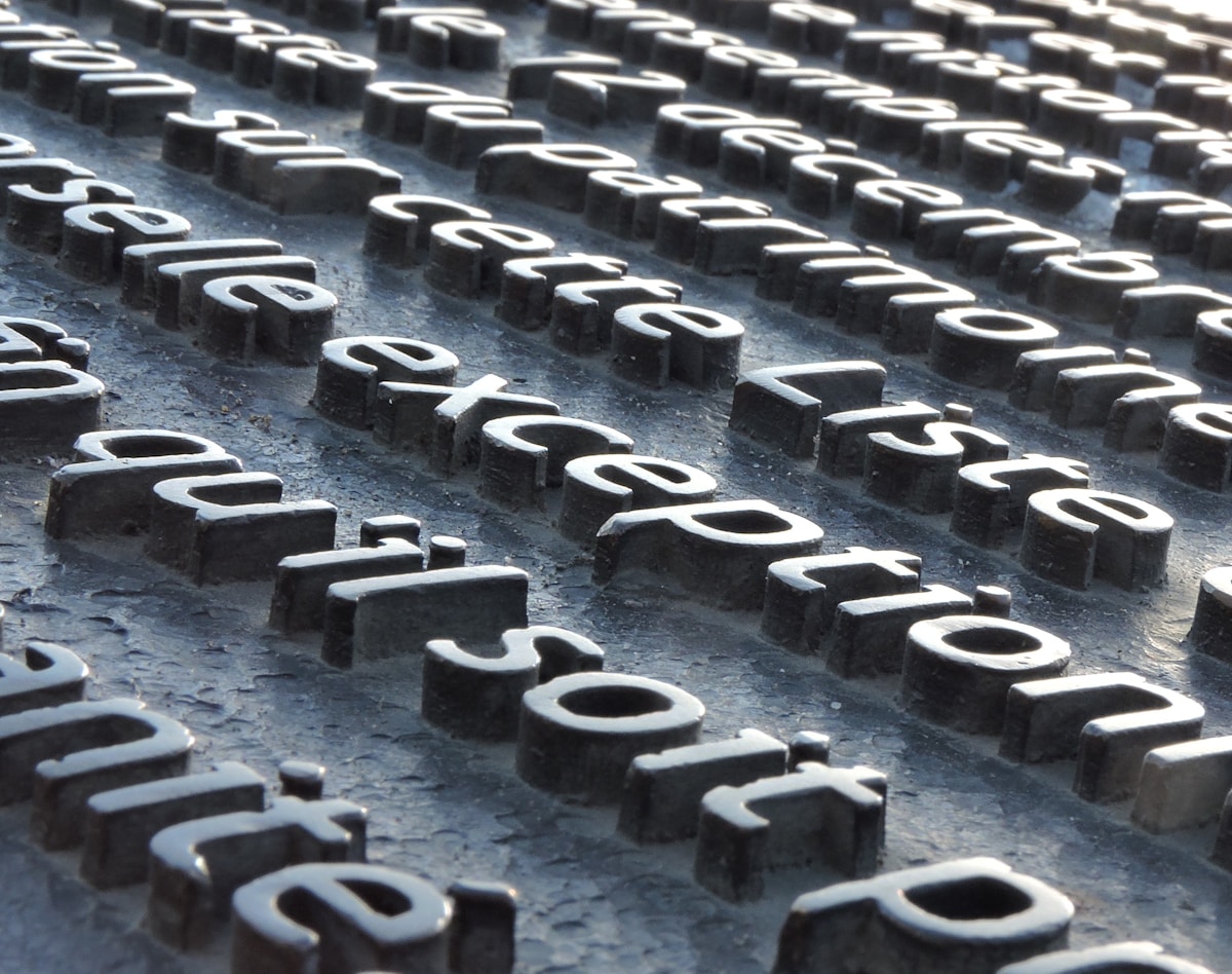 Blocs de lettres noires formant des mots sur un sol sombre.