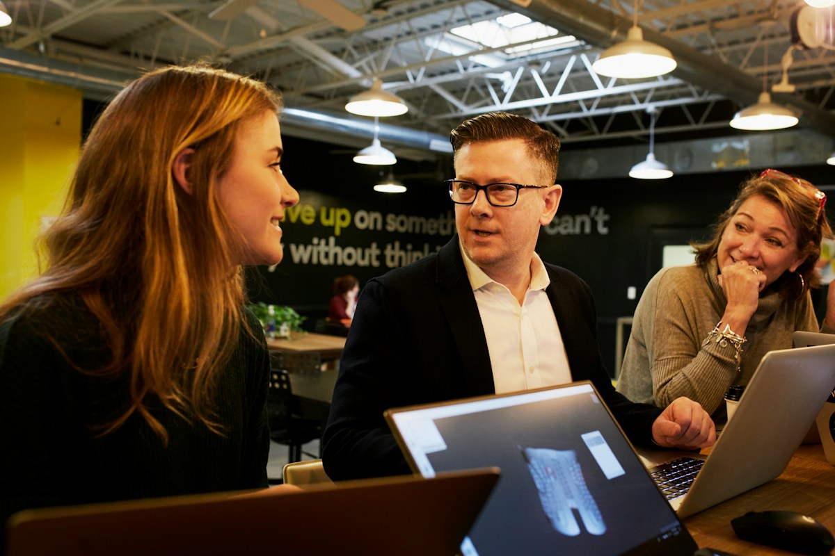 Équipe professionnelle discutant autour d’ordinateurs dans un espace de coworking