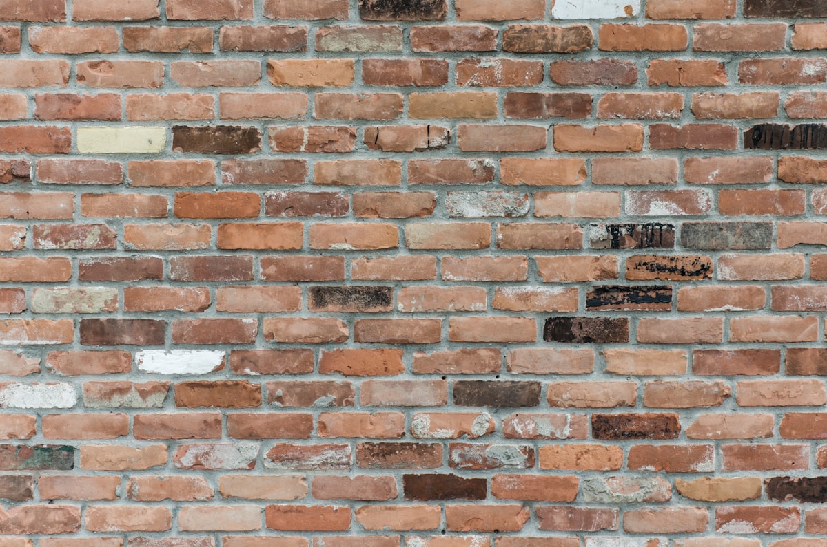 Mur de briques rouges et blanches usagées et irrégulières.