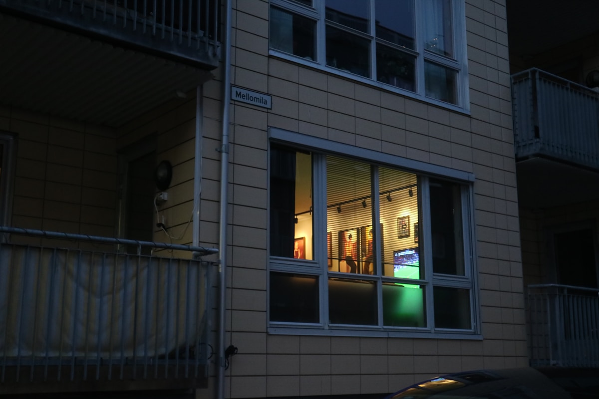 Bâtiment sombre avec fenêtres éclairées, affichage d'un match de football.