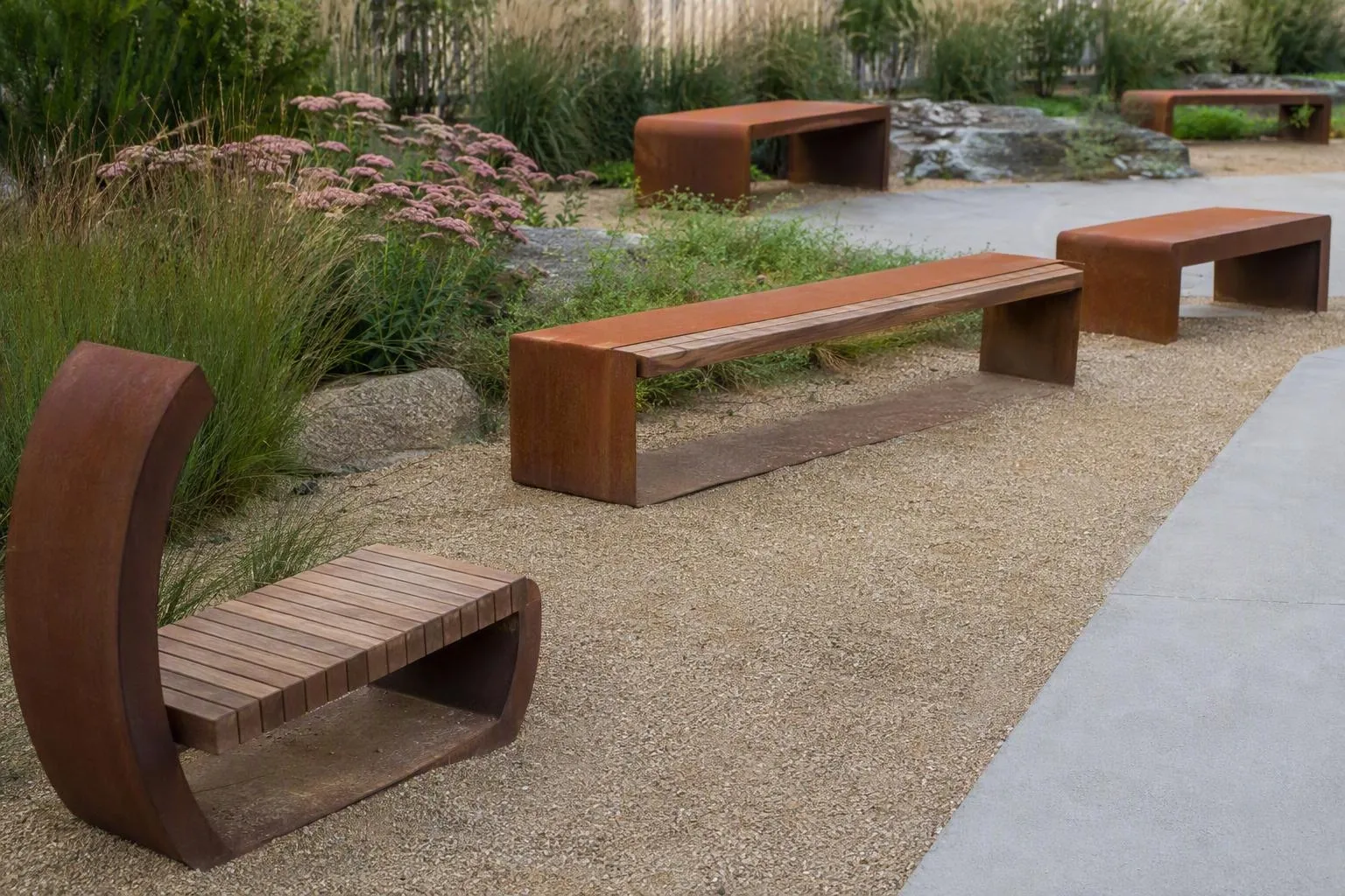 Bancs et tables en bois rouillé dans un jardin paysager.