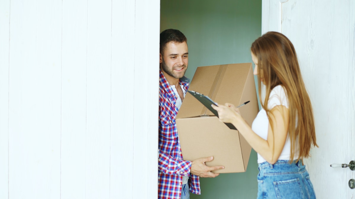 Couple heureux déménageant dans un nouvel appartement, portant des boîtes.