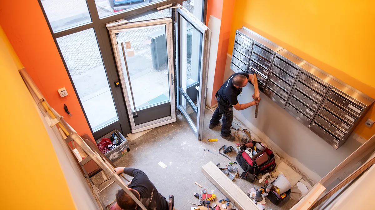 Réparation et rénovation d'un immeuble, ouvrier travaillant sur la porte d'entrée.