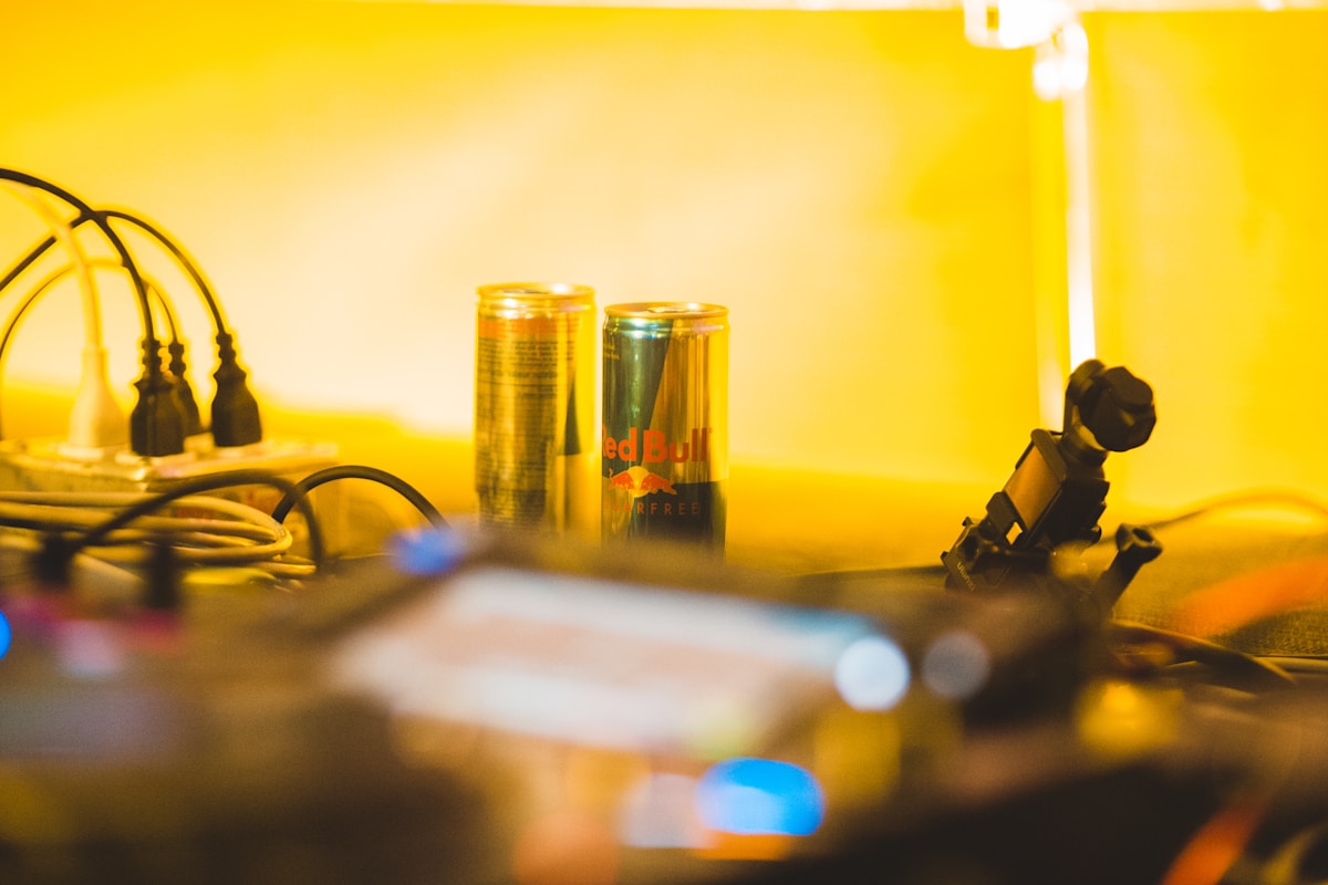 Câbles électriques, boissons énergisantes, lampe de bureau, espace de travail lumineux.