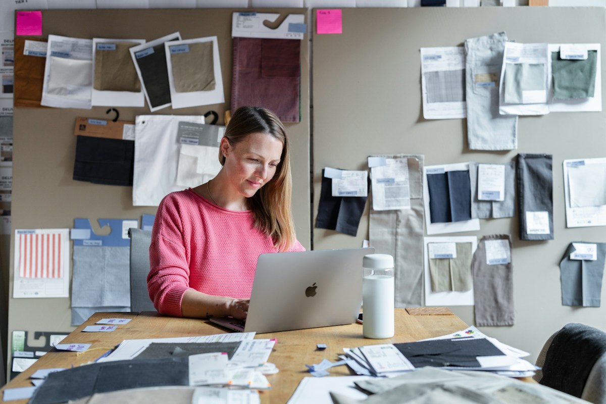 Femme travaillant sur ordinateur parmi des échantillons textiles.