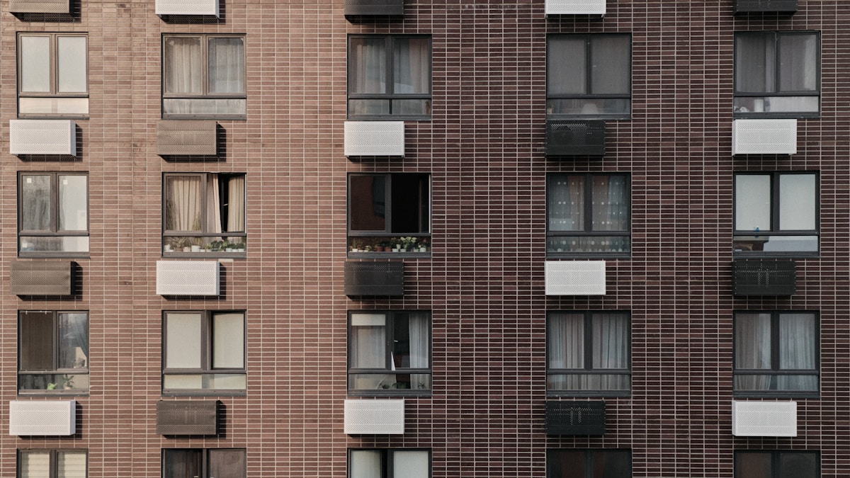 Façade de bâtiment en briques, fenêtres et balcons.