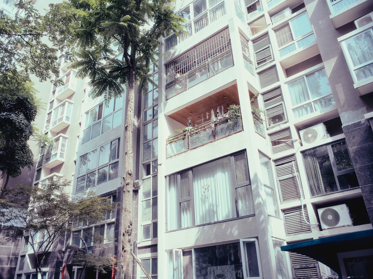 Immeuble résidentiel moderne avec balcons et palmiers.