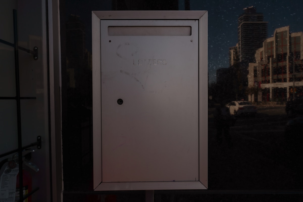 Boîte aux lettres blanche dans un environnement sombre.