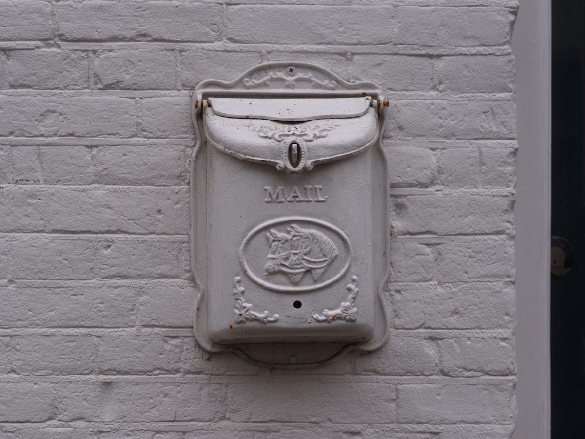 Boîte aux lettres vintage blanche sur un mur de briques.