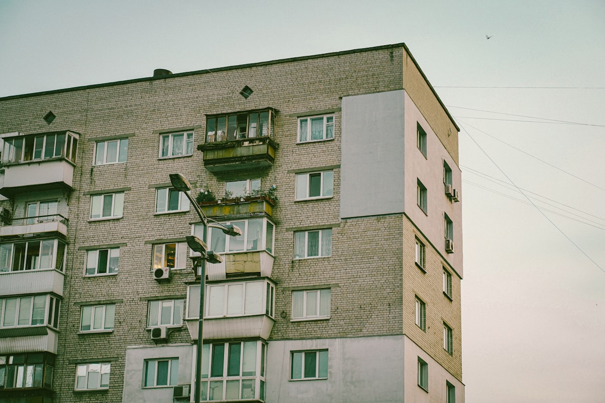 Immeuble d'appartements en briques vertes avec balcons et fenêtres.