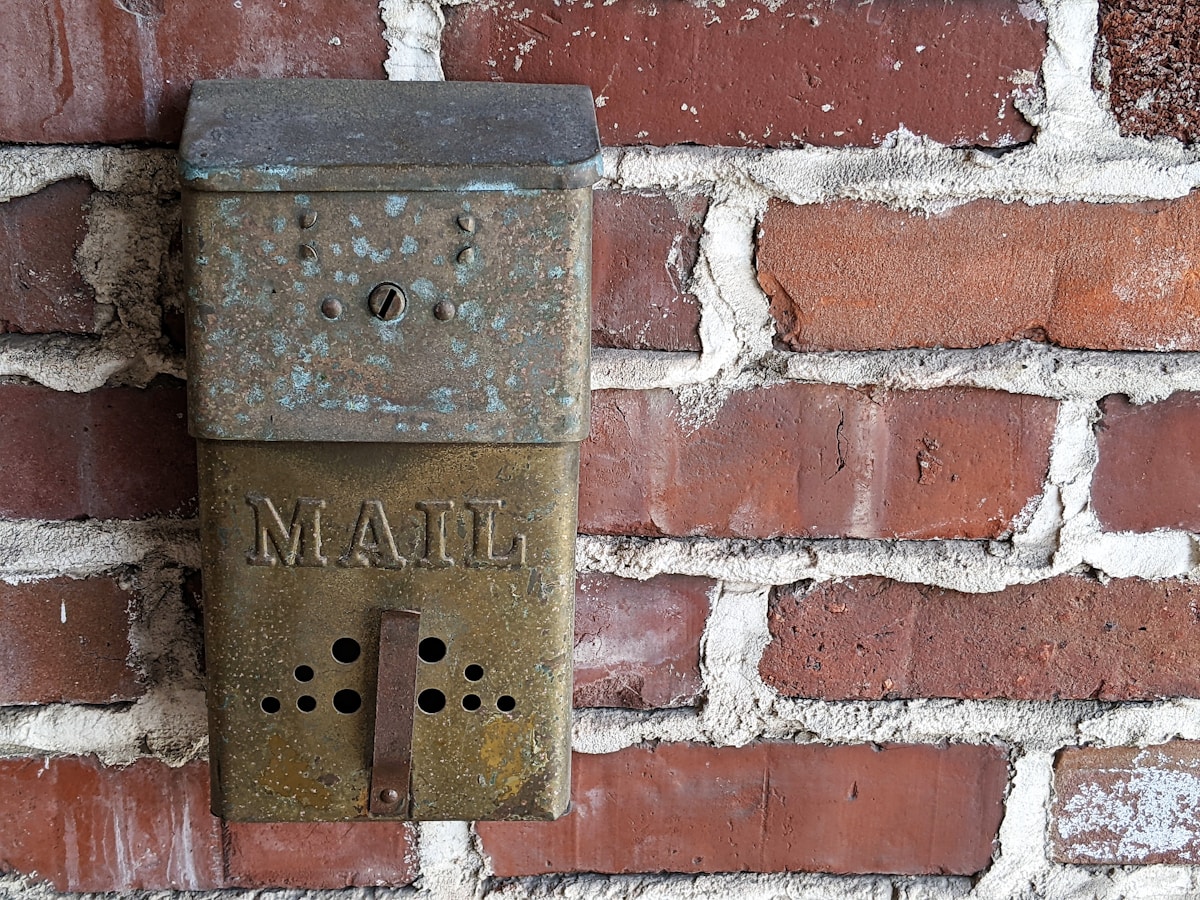 Boîte de courrier vintage en métal rouillé sur un mur de briques.