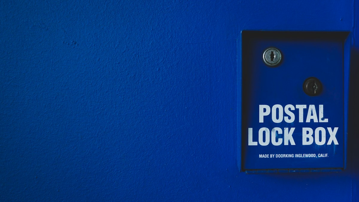 Boîte aux lettres bleue « Postal Lock Box » sur mur bleu