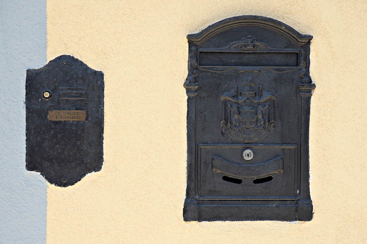 Boîte aux lettres ancienne en métal noir ornementée.
