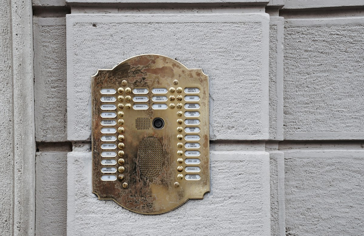 Interphone ancien en laiton fixé sur un mur en pierre.