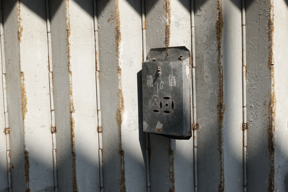 Boîte métallique rouillée suspendue sur un mur de bois désuet.