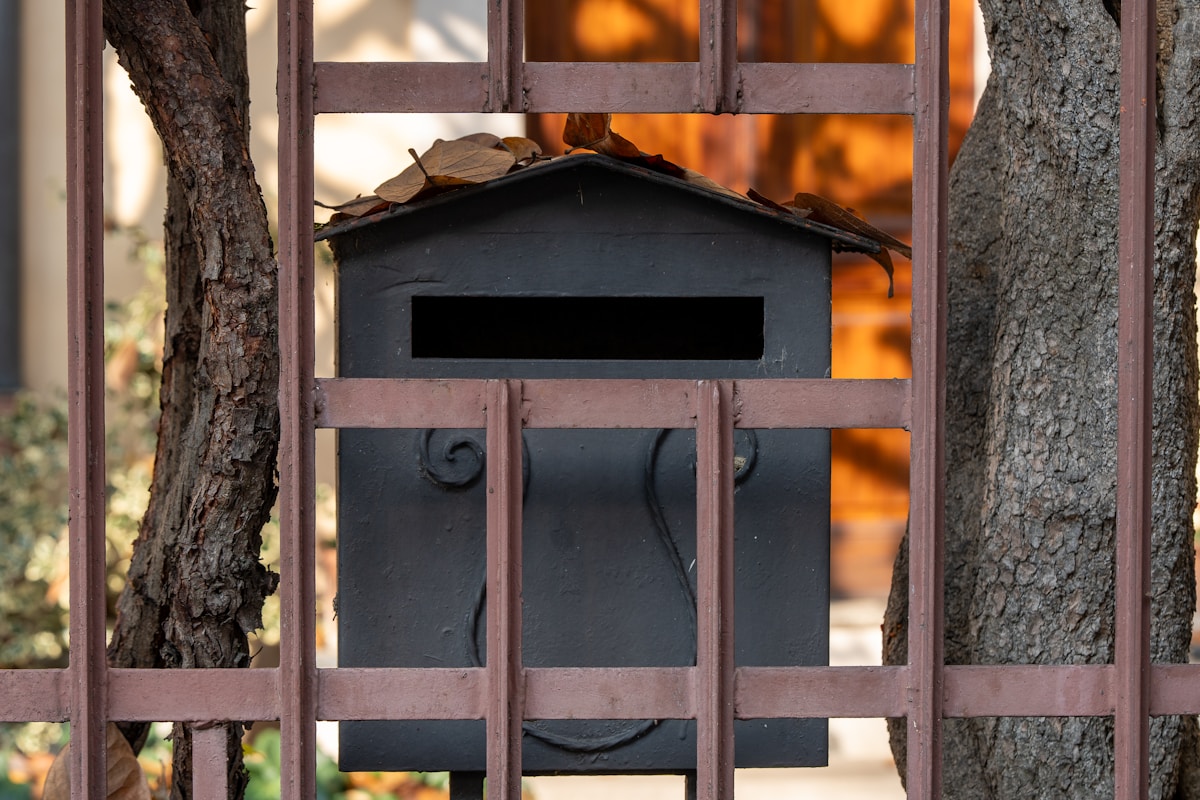 Boîte aux lettres noire rustique dans un cadre en bois.