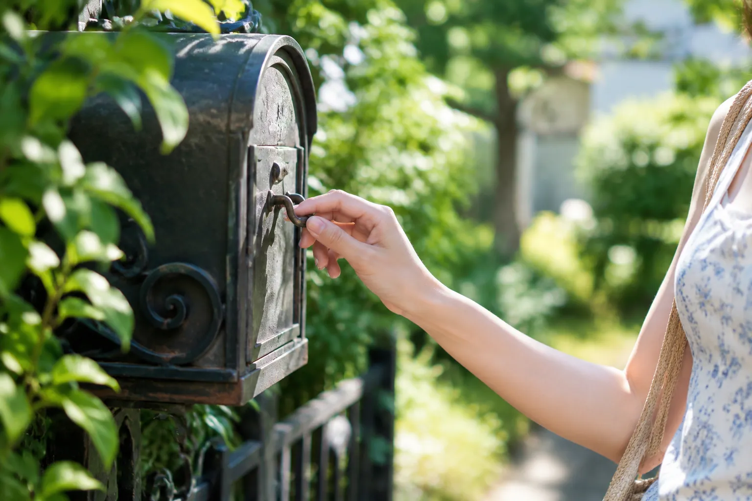 Main féminine répare la poignée de porte de boîte aux lettres pour éliminer son grincement.