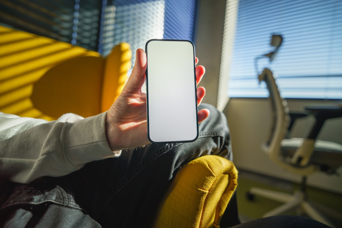Person holding a smartphone with a blank screen.