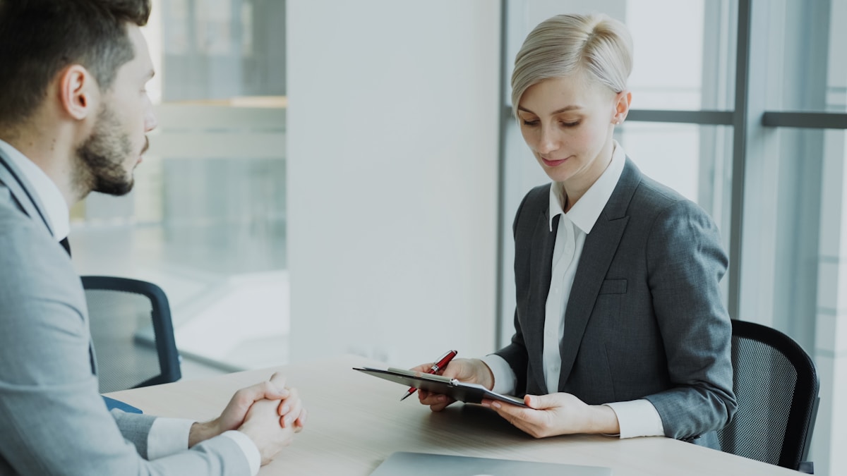 Woman in suit reviews document with man.