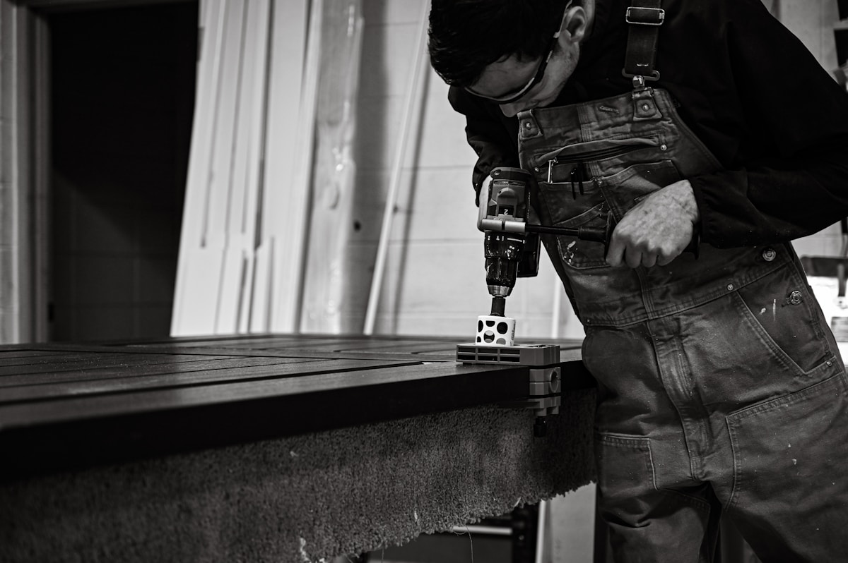 a man in overalls working on a piece of wood