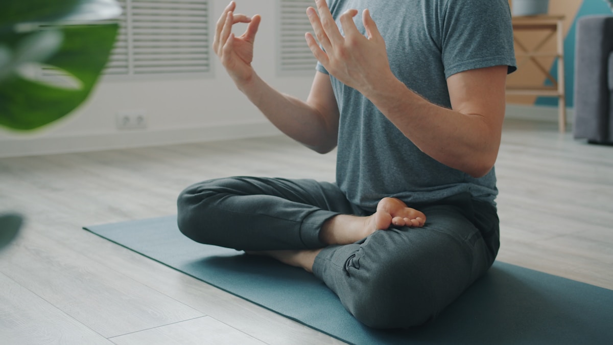 Man meditating in lotus pose on yoga mat.