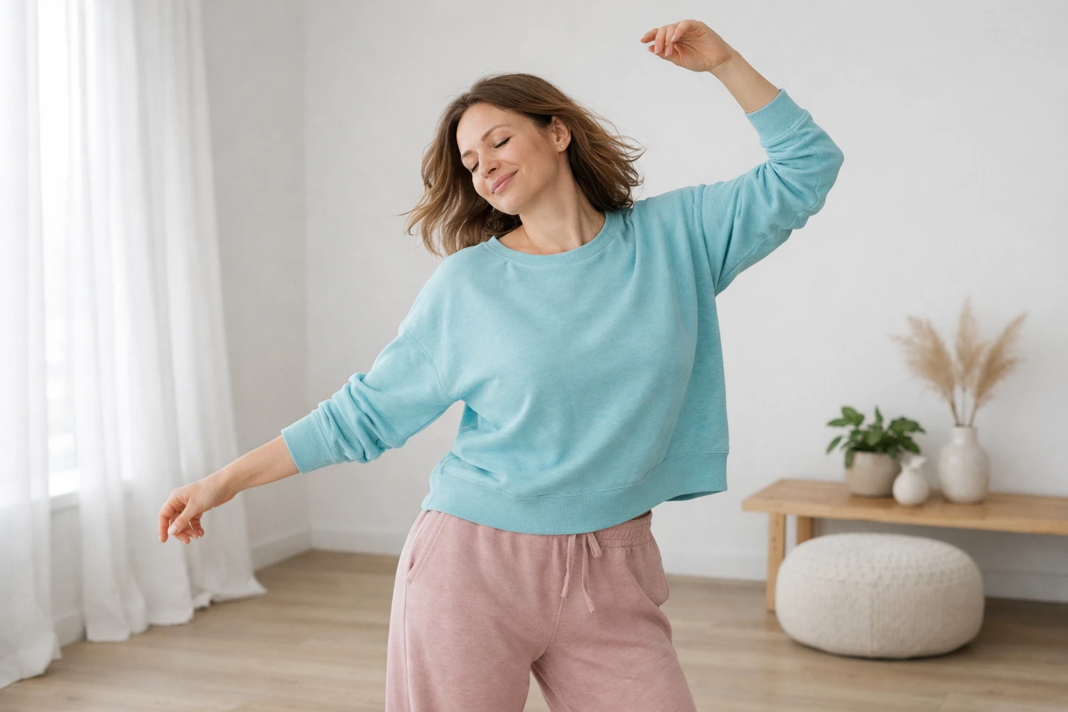 Adult woman in comfortable clothing moving freely with eyes closed in a bright, minimalist room with wooden floor, expressing joy and bodily freedom through spontaneous dance-like movements, arms extended naturally, serene facial expression showing reconnection with body sensations, warm natural lighting, emphasizing intuitive movement and physical safety