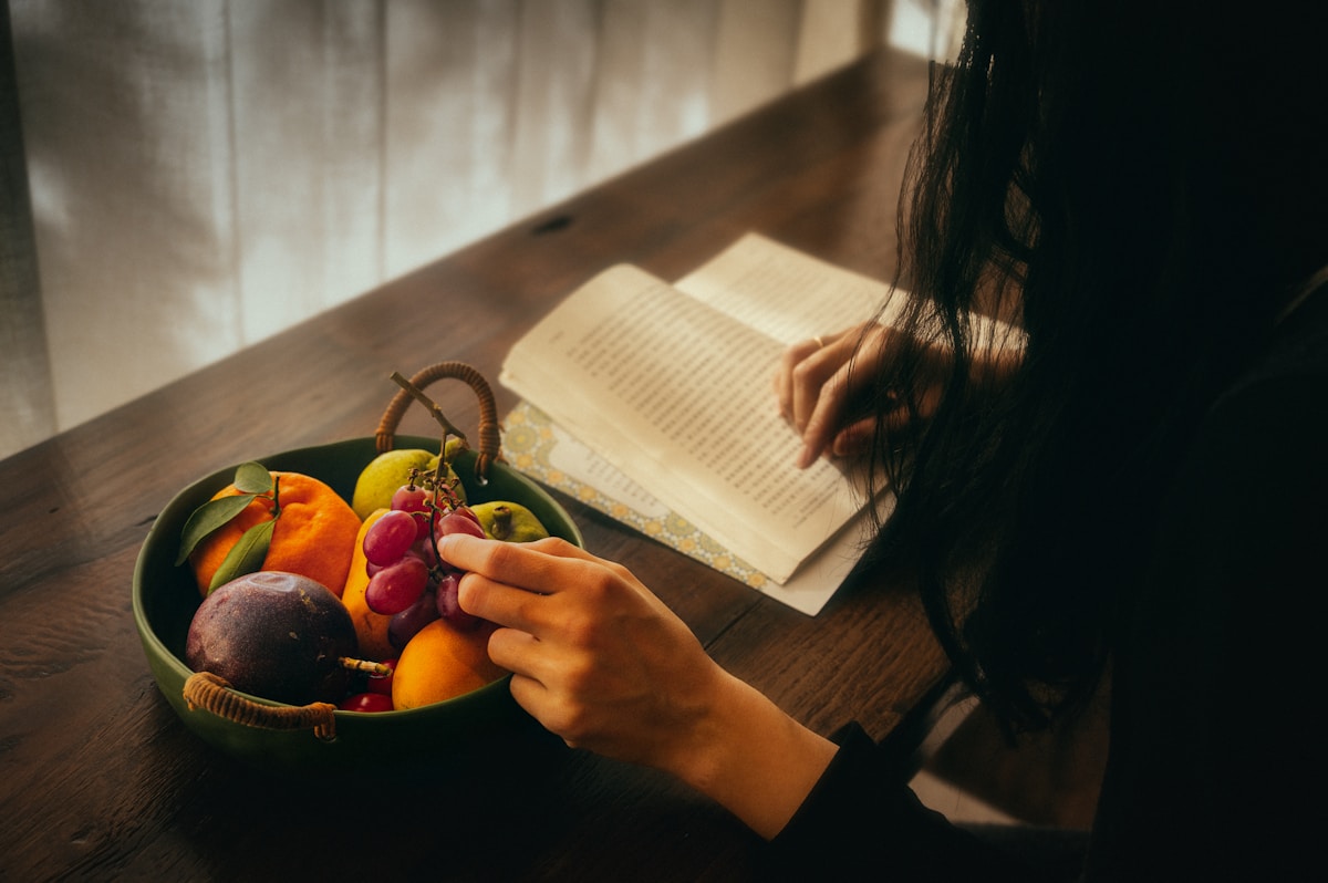 Person reading by a bowl of fruit