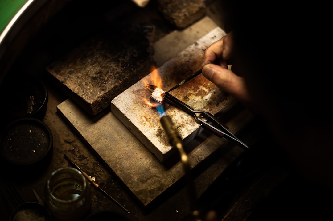 Un bijoutier qualifié façonne une alliance mariage en or avec précision dans un atelier traditionnel, ambiance chaleureuse -