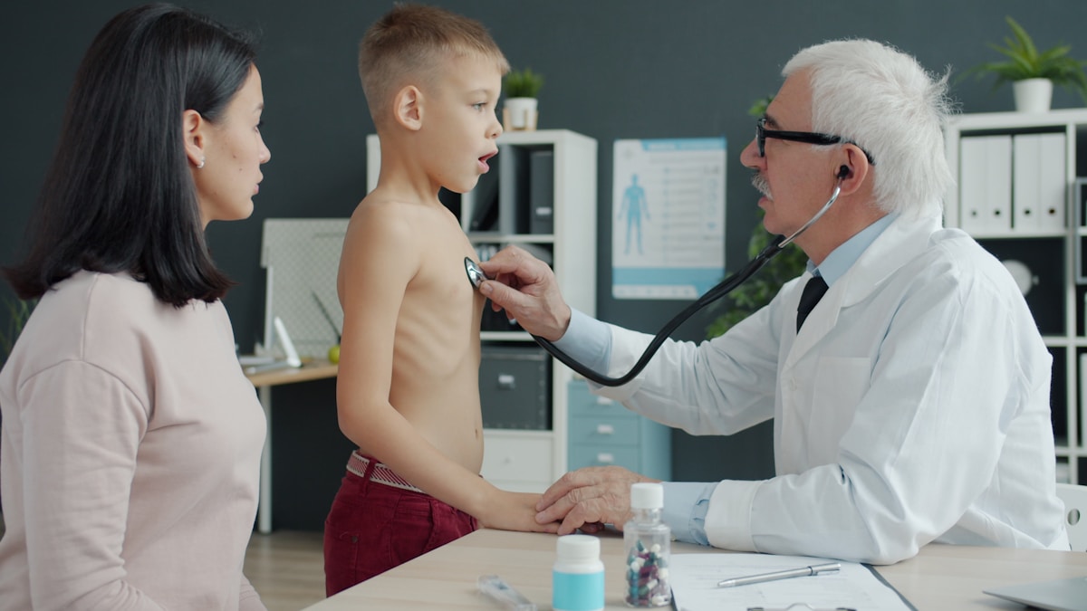 Médecin examinant un jeune patient dans une salle de consultation.