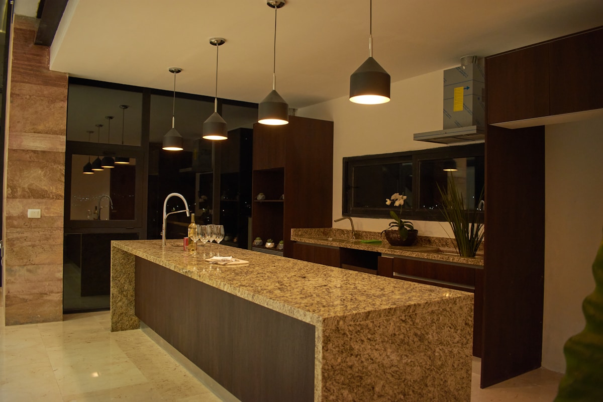 Cuisine moderne avec comptoir en granite et luminaires suspendus.