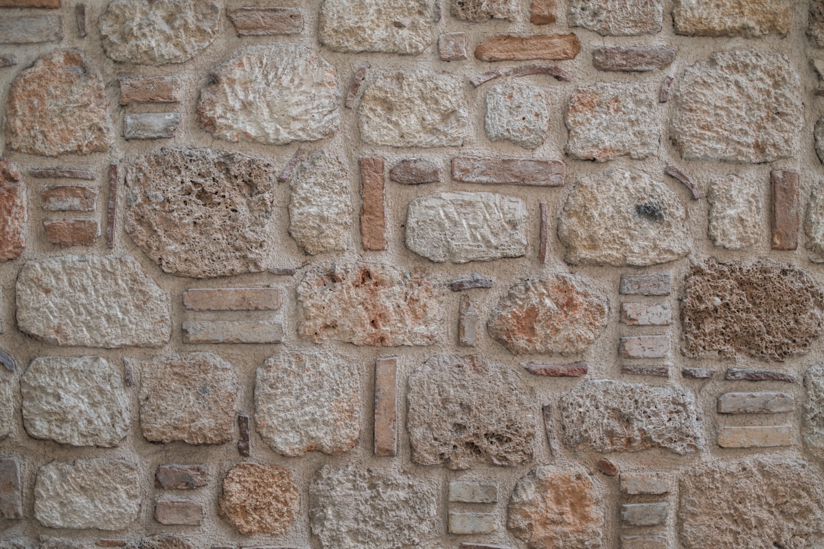 Mur de pierres irrégulières, textures et couleurs variées.