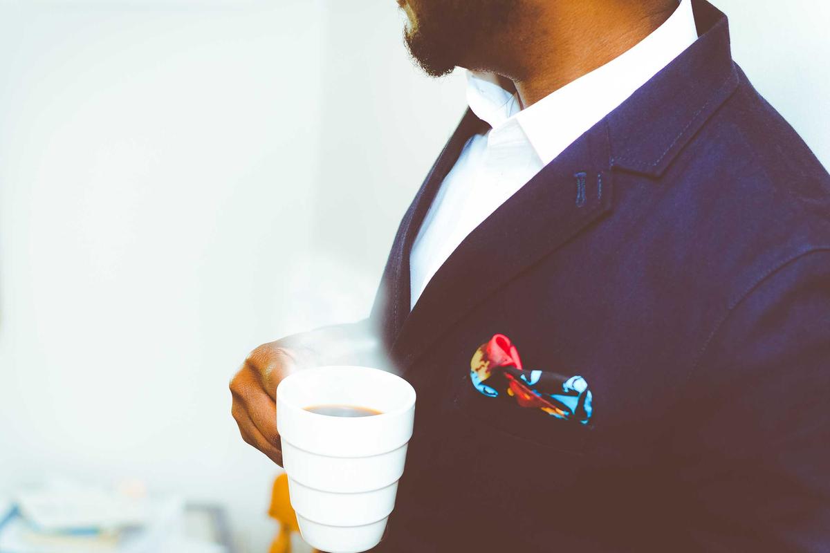 A person in a suit holding a coffee cup.