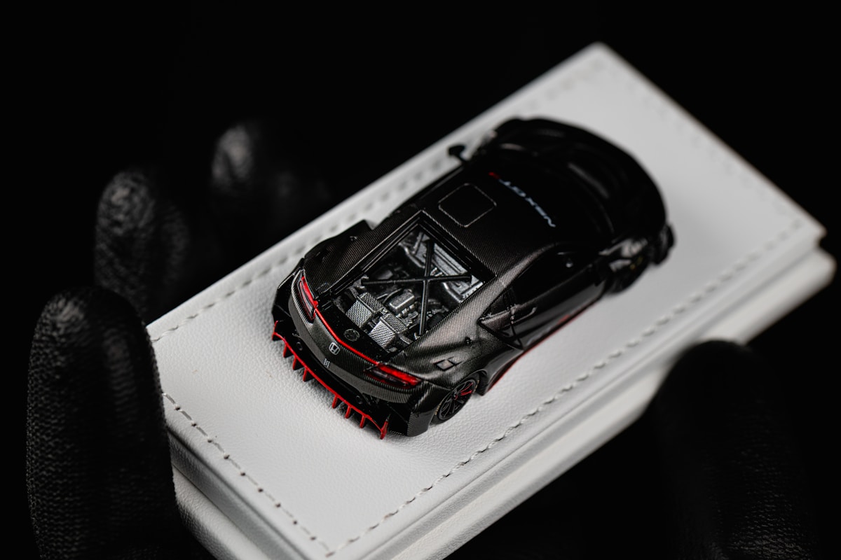 Black toy car with red accents on white surface.