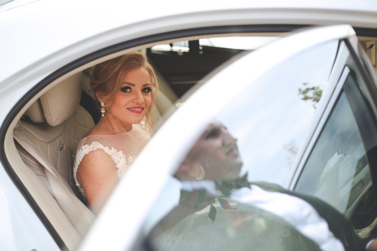 Mariée souriante dans une voiture de mariage.