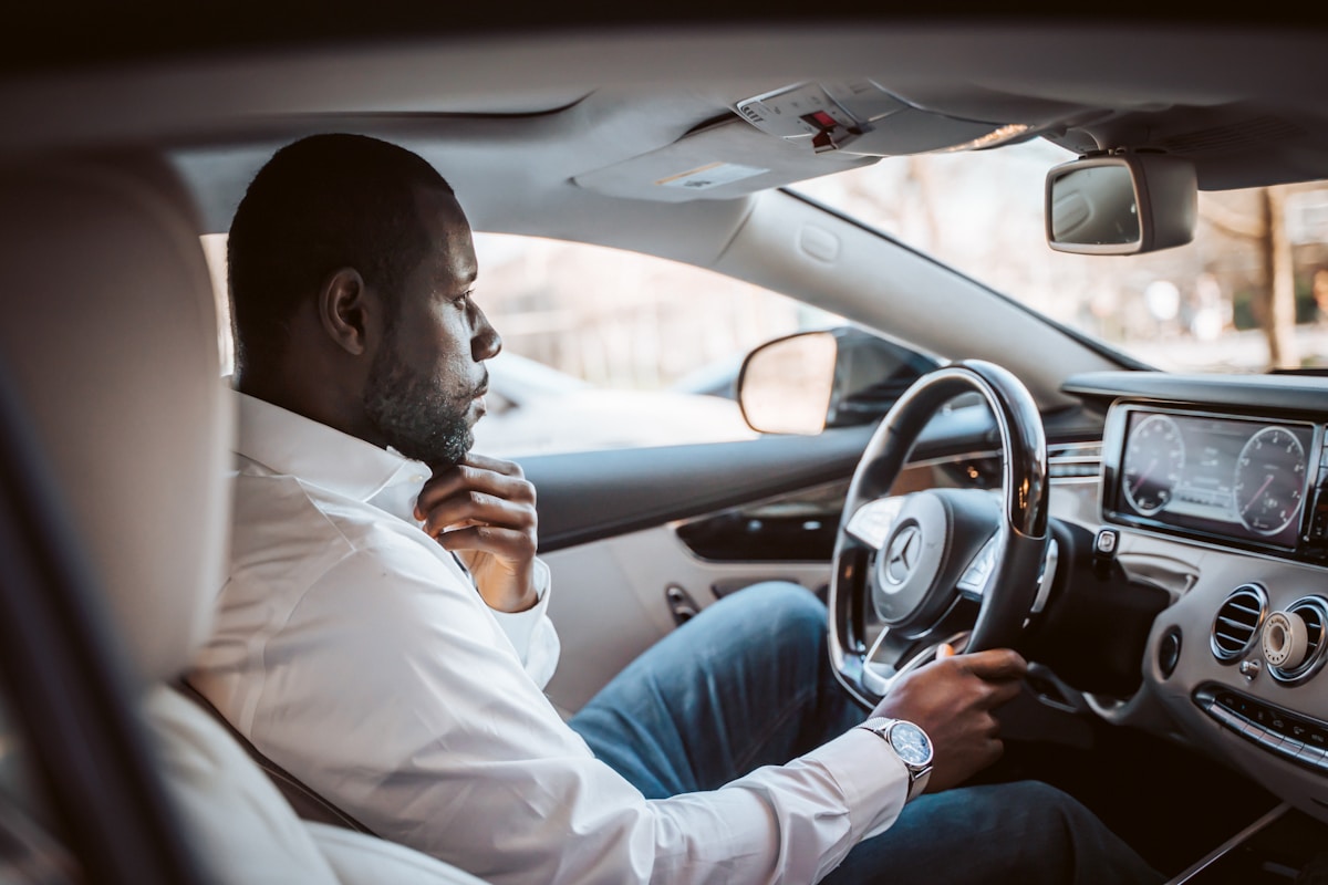 Homme d'affaires conduisant une voiture de luxe avec attention.