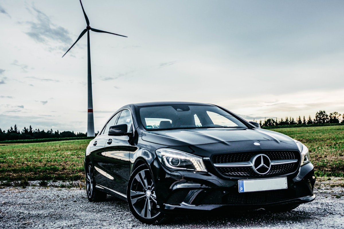 Voiture Mercedes-Benz CLA noire élégante devant une éolienne.