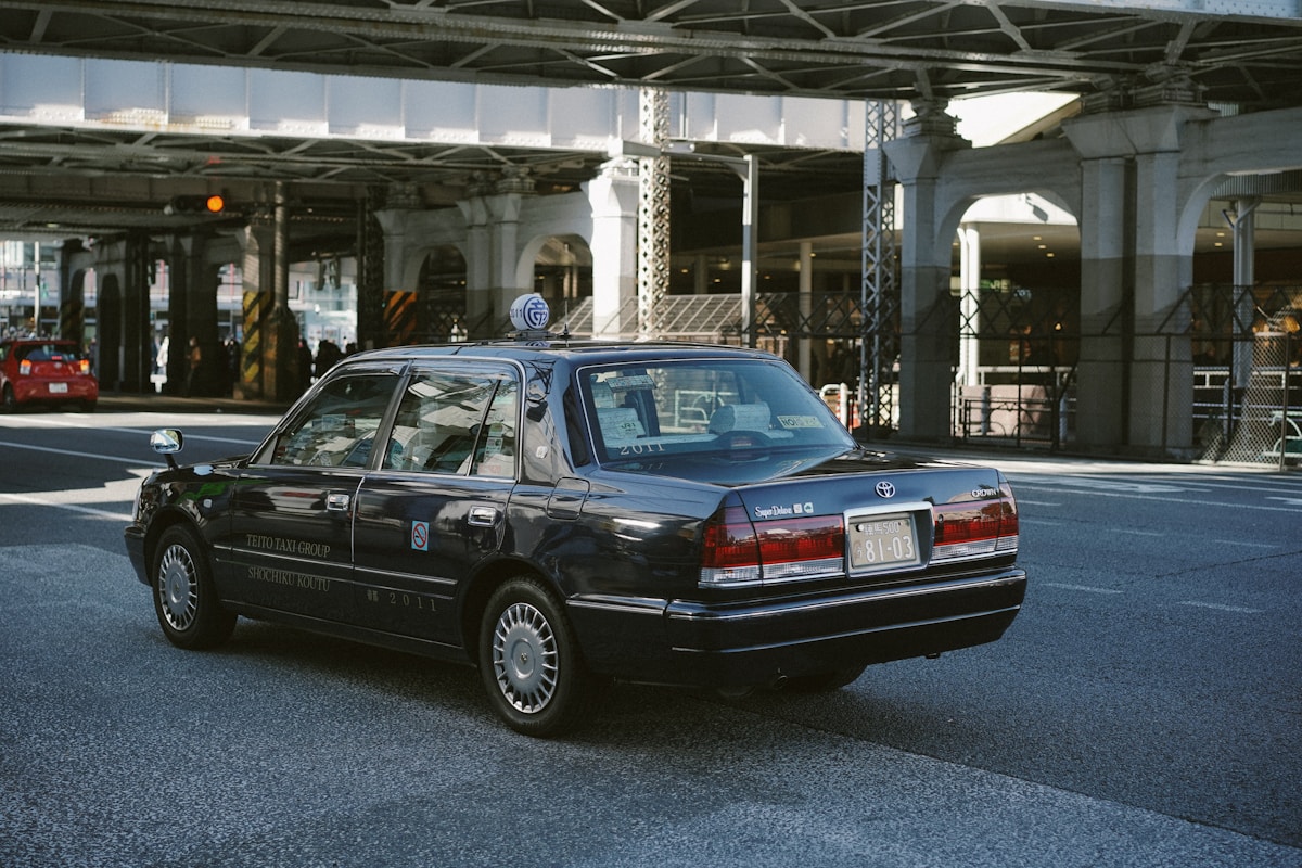 Taxi noir Toyota Crown stationné dans un aéroport moderne.