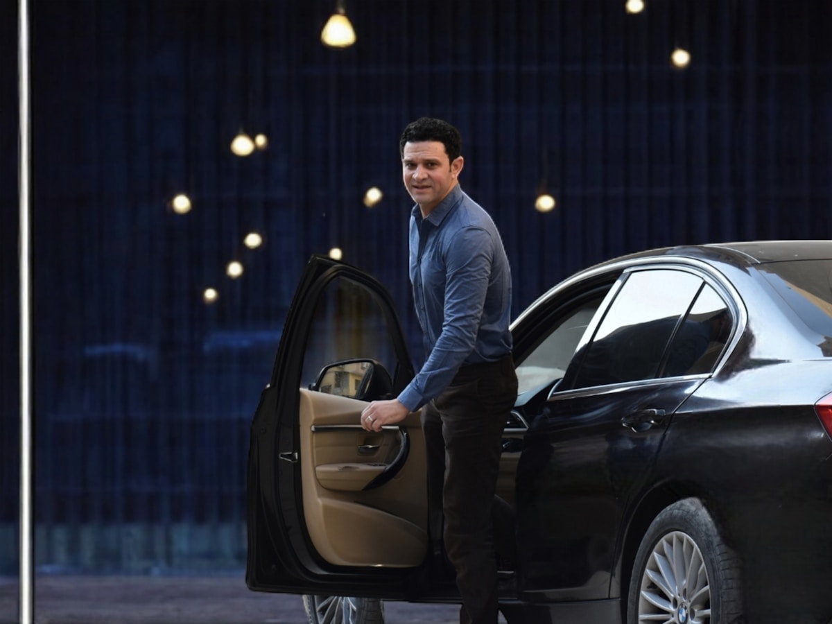 Homme élégant sortant d'une voiture de luxe dans un endroit sombre.