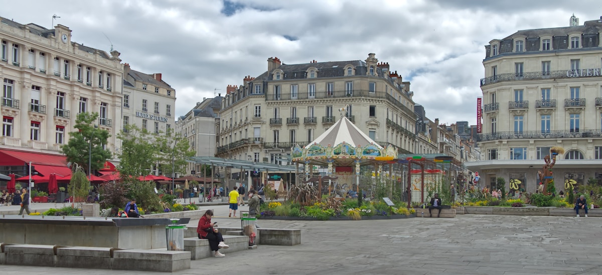 Place publique animée avec carrousel, cafés et bâtiments historiques.