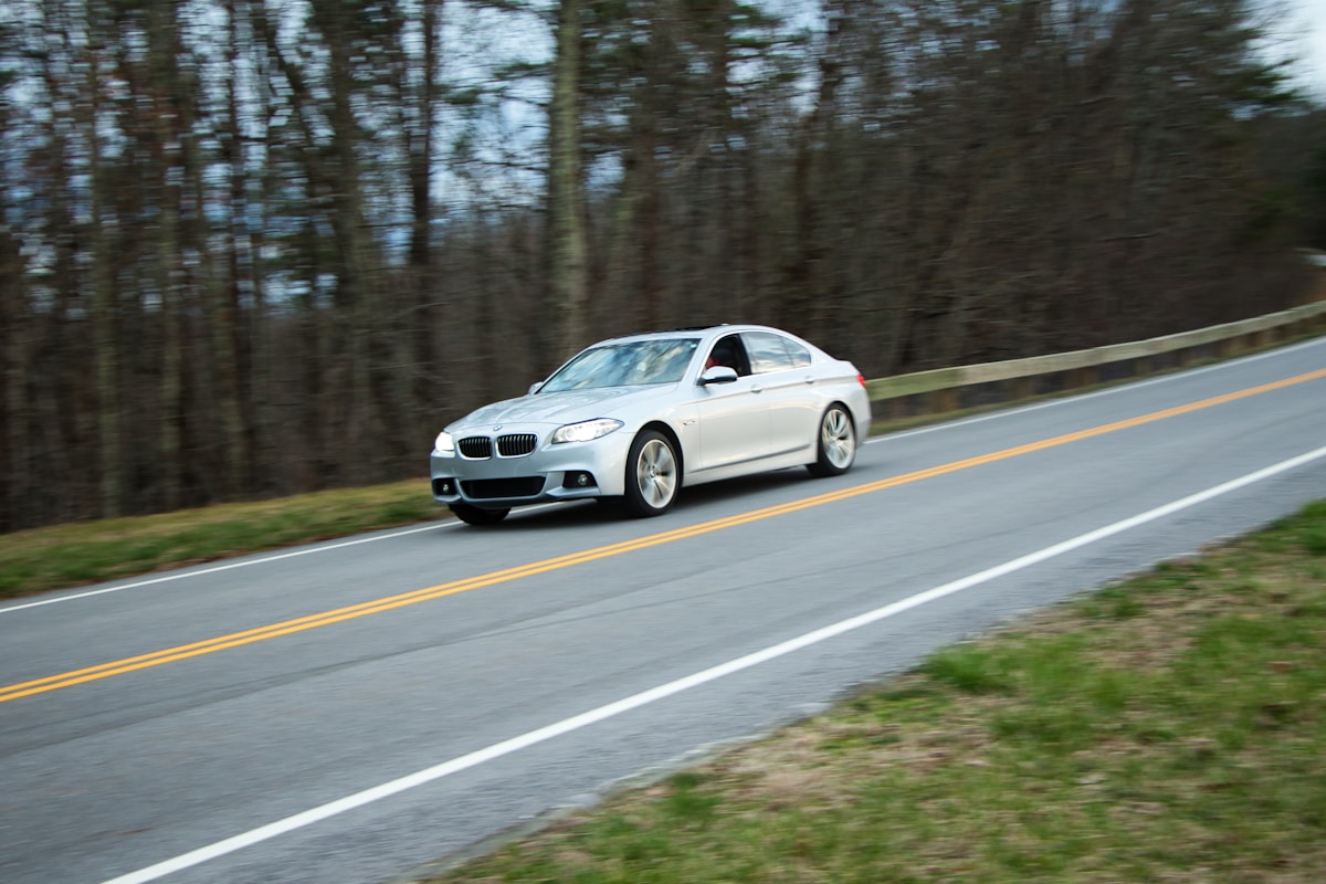 Voiture BMW blanche roulant sur une route de campagne.
