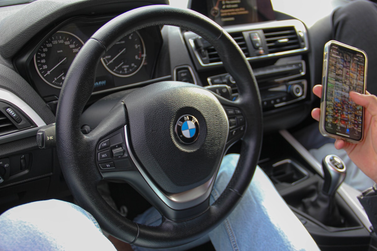 Intérieur d'une voiture BMW avec volant, tableau de bord et smartphone.
